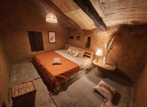 Una camera accogliente con un letto, un comodino, una lampada e un piccolo tappeto.