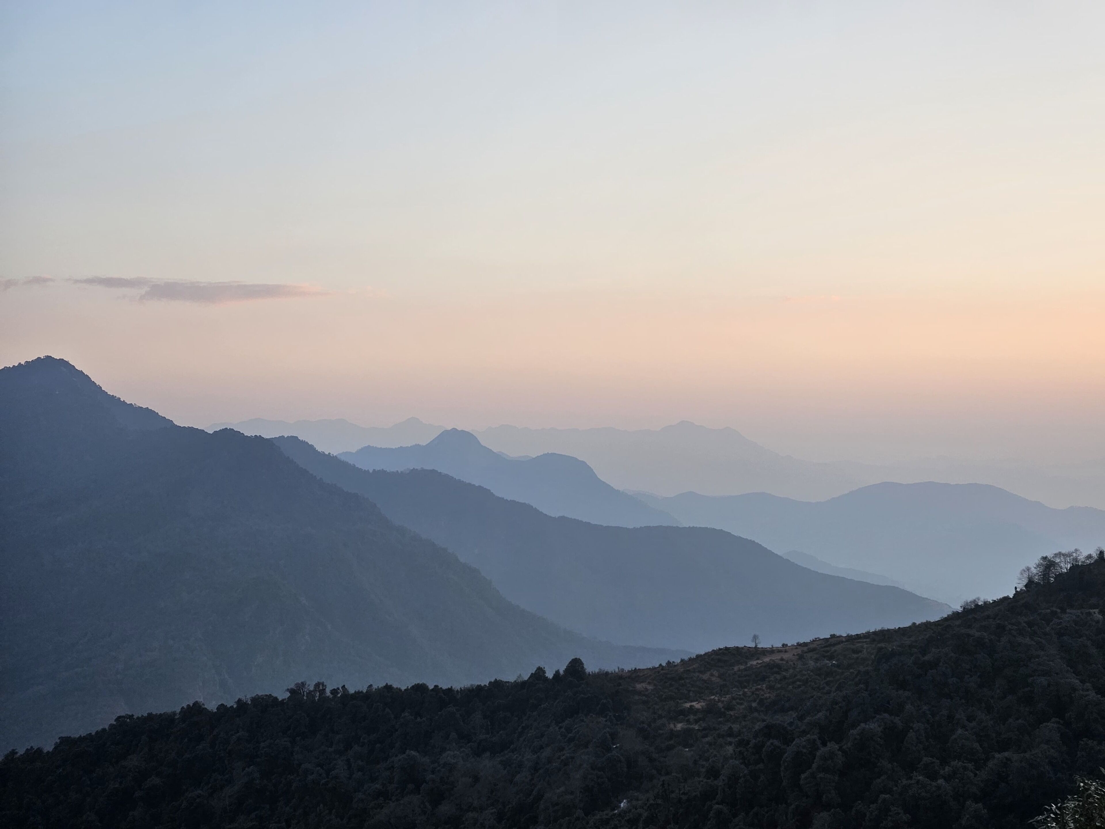 A mountainous landscape with multiple peaks and a forested foreground.