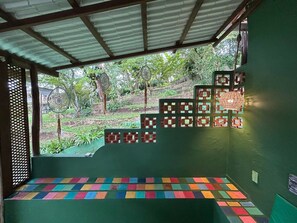 Quarto com parede verde, piso estampado e vista para o exterior com vegetação.