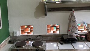 Una cocina con estufa, un colgador para ollas y una ventana con celosía decorativa.