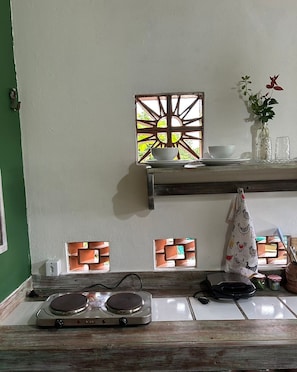 Cozinha com fogão, aramado para panelas penduradas e janela com um biombo decorativo.