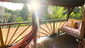 Una hamaca bajo una estructura de madera con una cama y vistas al verdor.