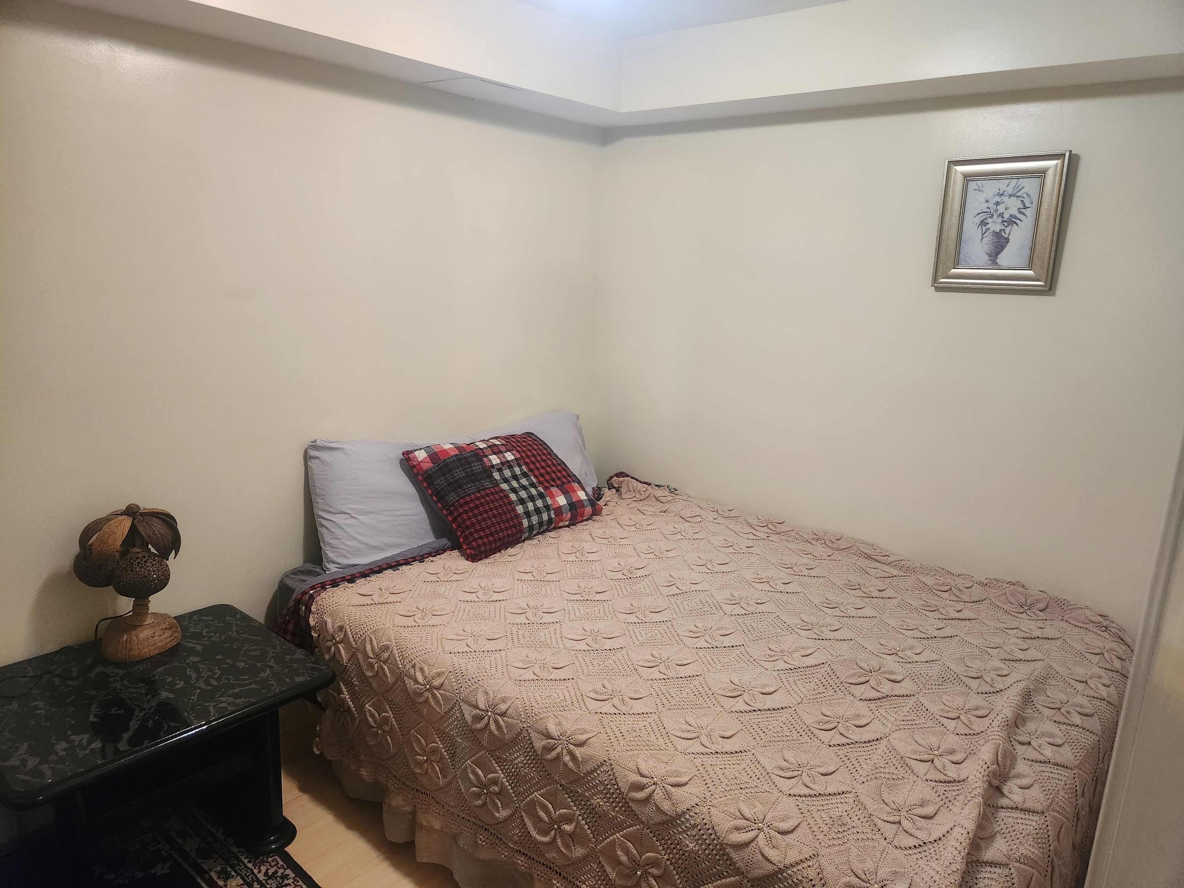 Un dormitorio pequeño y ordenado con una cama individual, una mesita de noche y un cuadro colgado en la pared.
