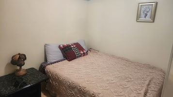Un dormitorio pequeño y ordenado con una cama individual, una mesita de noche y un cuadro colgado en la pared.