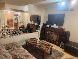 Ein Wohnzimmer mit einer Couch, einem Couchtisch, einem Kamin, einem Fernseher und einem großen Spiegel.