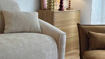 Un salon moderne avec un canapé, un fauteuil, un meuble en bois et une lampe.