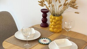 Una mesa de comedor con dos sillas, un jarrón con flores secas, una vela y una copa de vino.