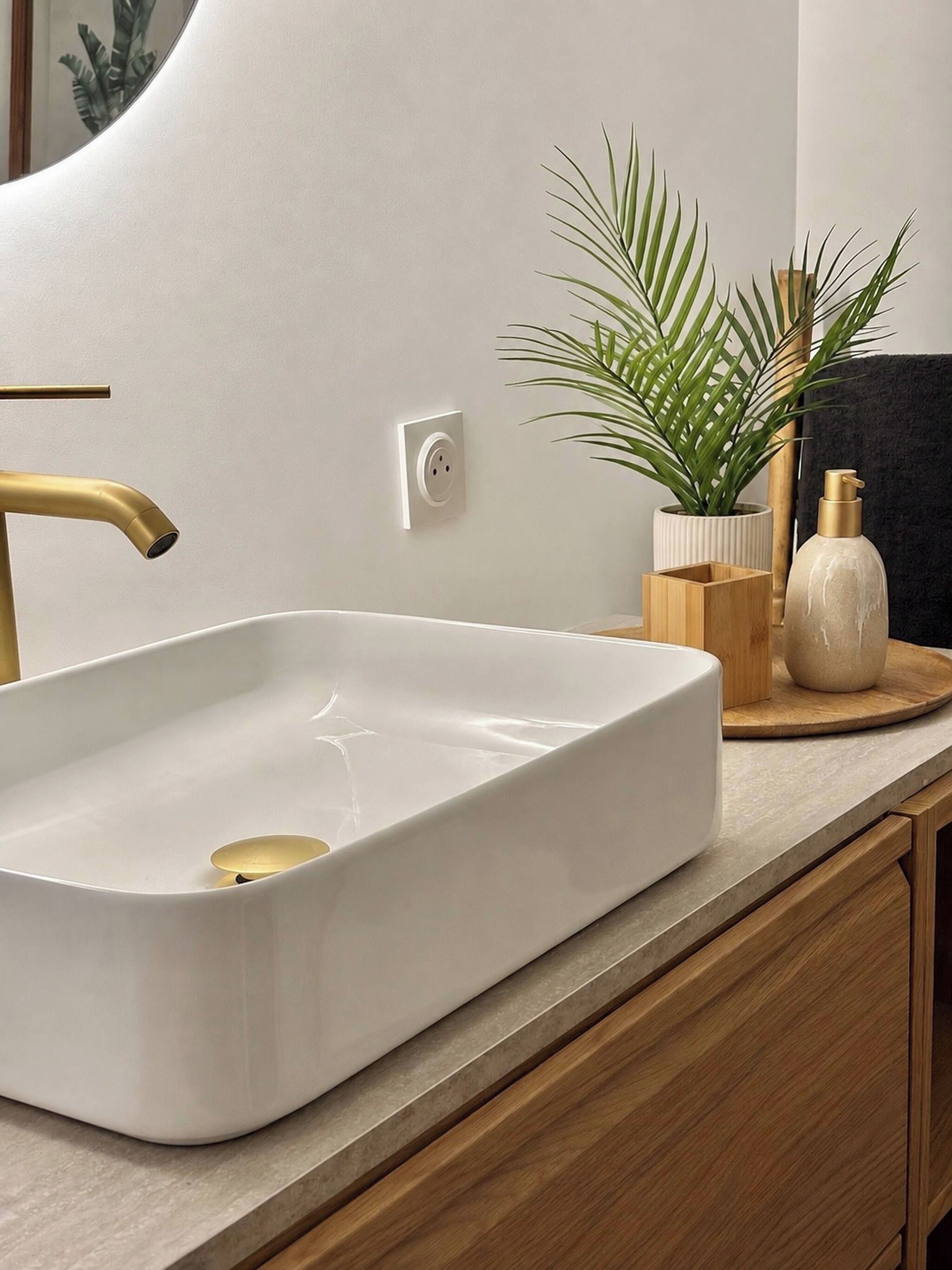 A white rectangular sink with a gold faucet on a countertop.
