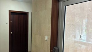 Un pasillo con una puerta de madera, una puerta de cristal con respiradero y suelo de baldosas.
