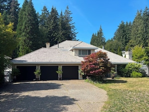 A two-story house with a covered garage, surrounded by trees and a well-maintained lawn. - Luxe 4Bdr West Vancouver Home Hiking & Bike Trails + Lake + Ocean+ Pool + Skiing (West Vancouver)