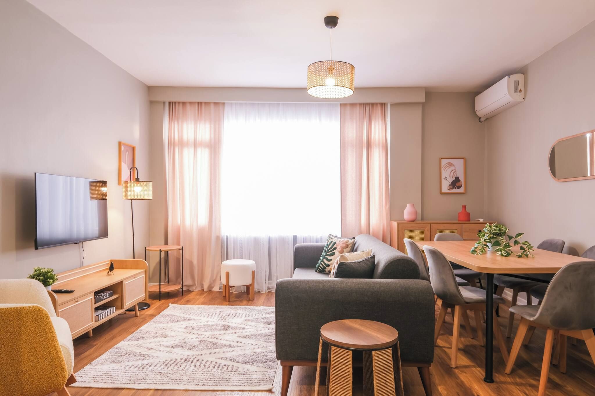 A modern living room with a flat-screen TV, sofa, dining table, and chairs.