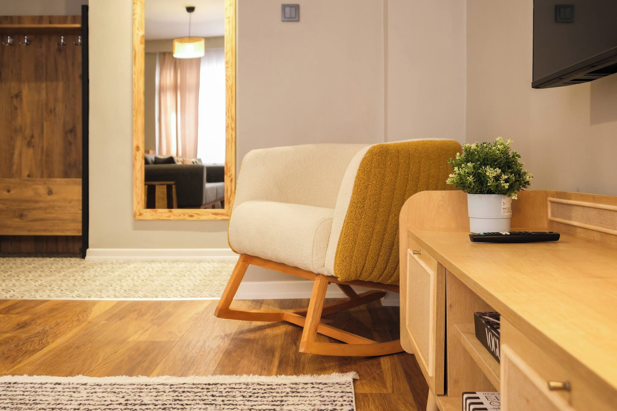 A modern living room with a sofa, a wooden coffee table, a potted plant, and a television mounted on the wall.