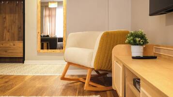 A modern living room with a sofa, a wooden coffee table, a potted plant, and a television mounted on the wall.