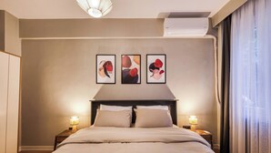 A hotel room with a large bed, two bedside tables with lamps, a ceiling light, and three abstract paintings on the wall. - Modern, 3BR, Best Location (Kadıköy)