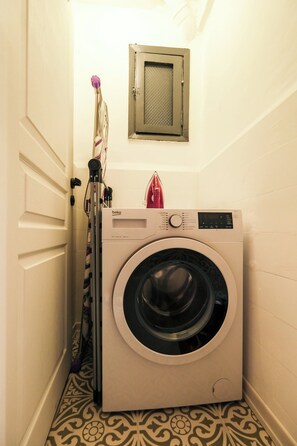 A compact laundry room with a front-loading washing machine, a drying machine, and a small ventilation window above the washing machine. - Modern, 3BR, Best Location (Kadıköy)