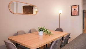 A conference room with a wooden table, chairs, a potted plant, a mirror, a floor lamp, and a framed picture on the wall. - Modern, 3BR, Best Location (Kadıköy)