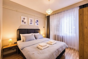 A neatly made bed with pillows and towels, a bedside lamp, and artwork on the wall. - Modern, 3BR, Best Location (Kadıköy)