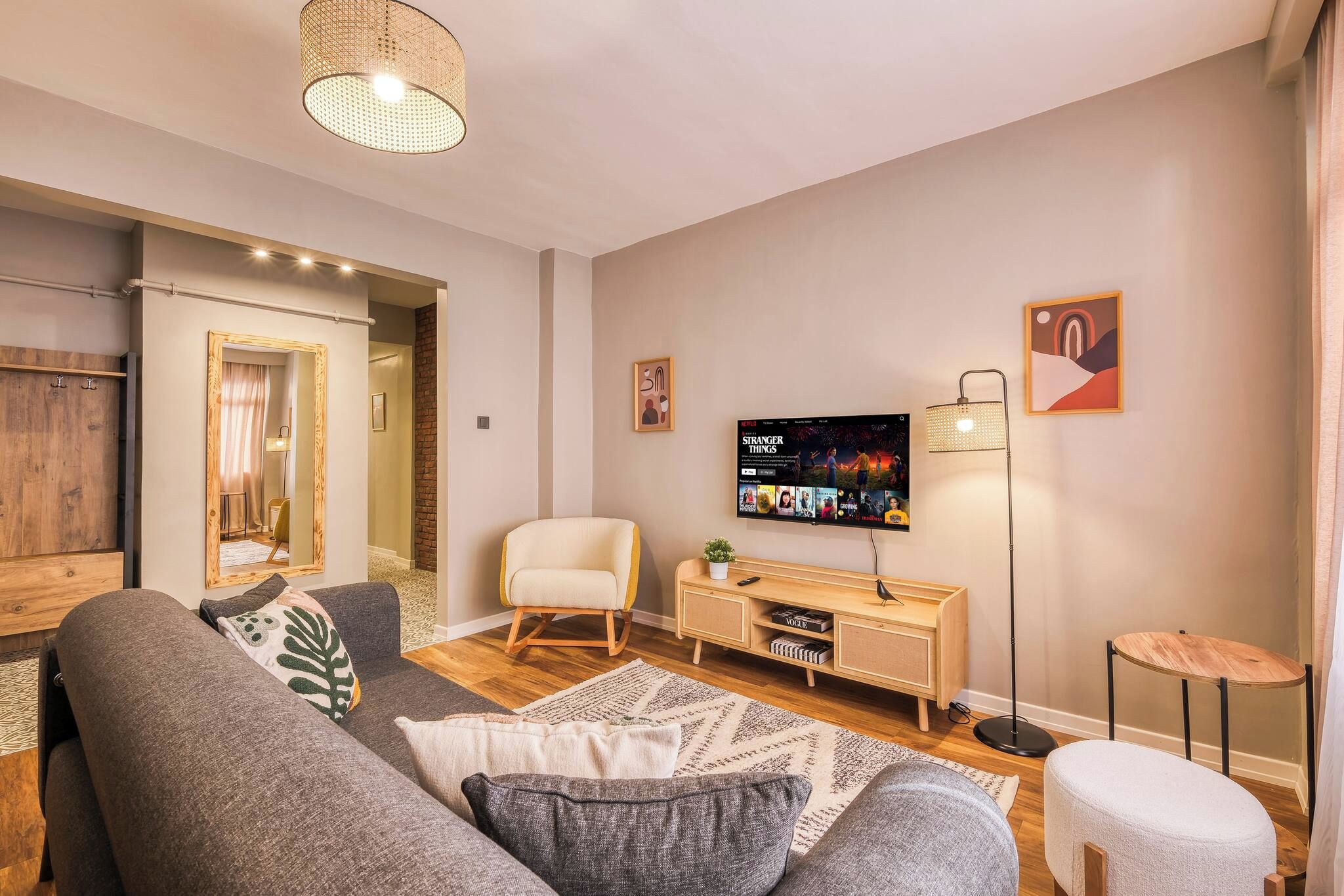 Un salon moderne avec un canapé, un fauteuil, un téléviseur et une petite table.
