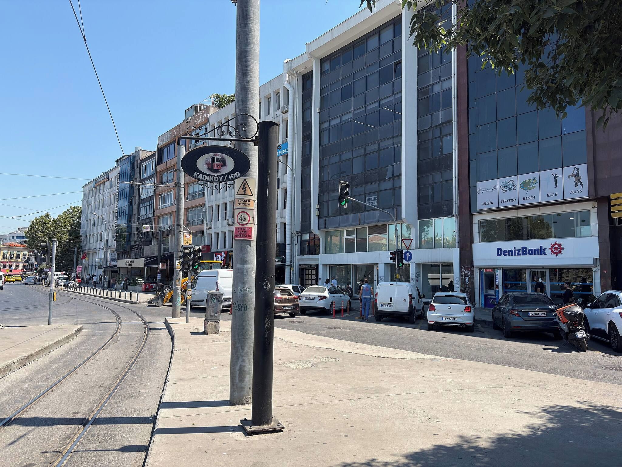 Vista de una calle con tranvía, un banco y diversas tiendas.