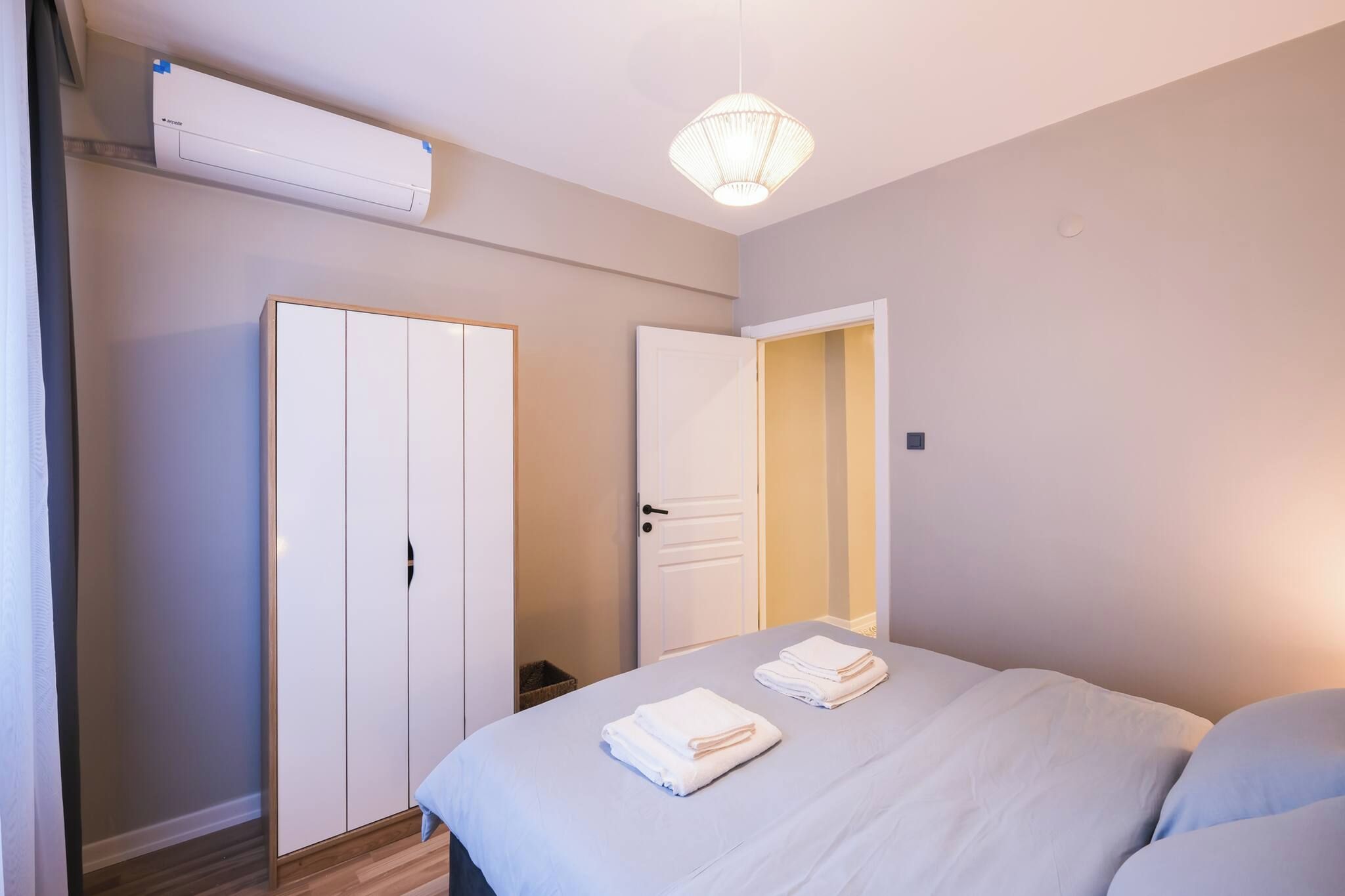 Ein Schlafzimmer mit einem Bett, einem Kleiderschrank und einer Tür zu einem weiteren Raum.