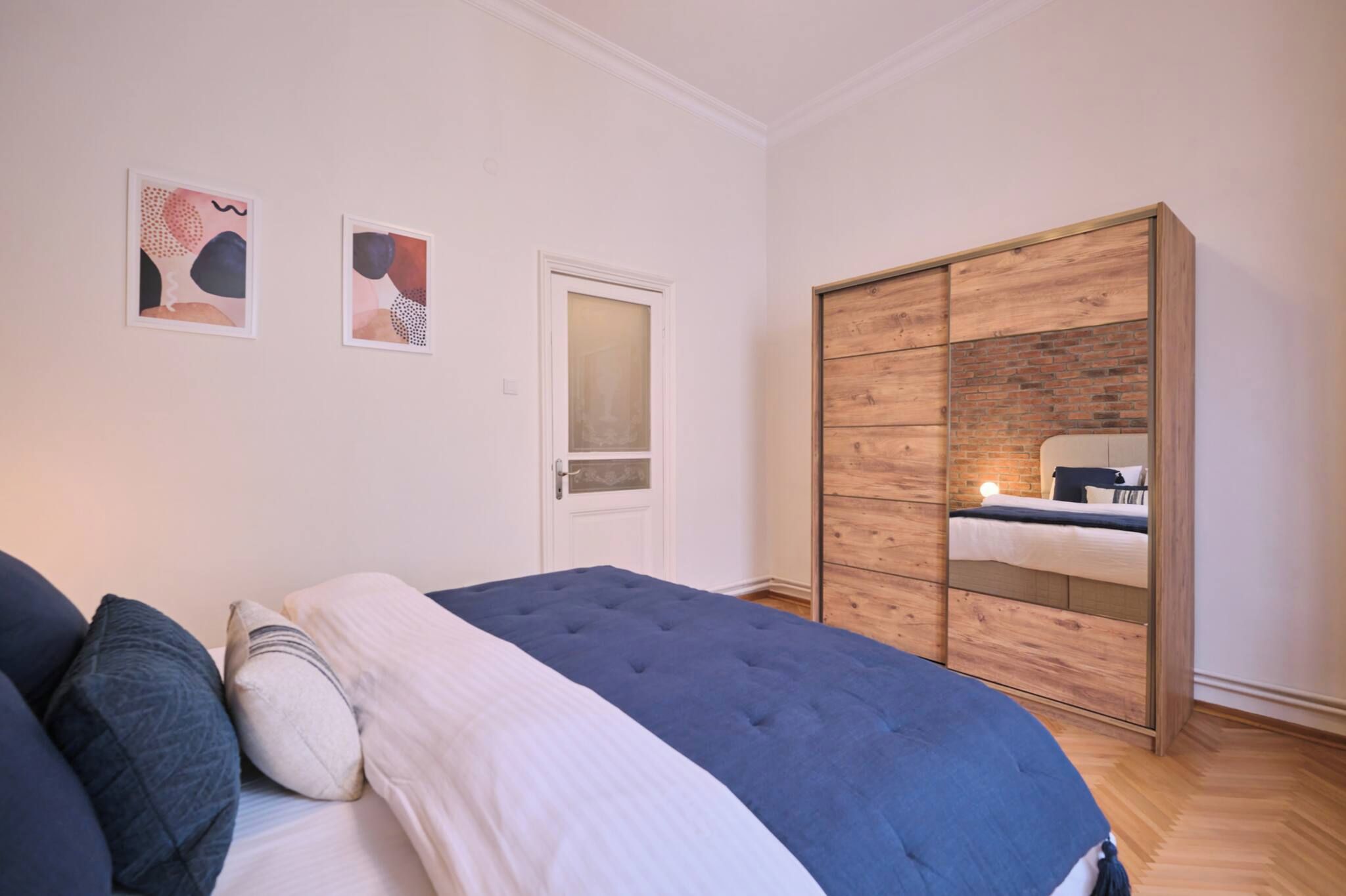 Een slaapkamer met een bed, een kledingkast en twee kunstwerken aan de muur.