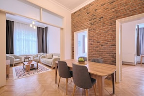 A modern living room with a dining area, a brick wall, and a large window. - Historical Building at the Iconic Tram Street, 3BR (Kadıköy)