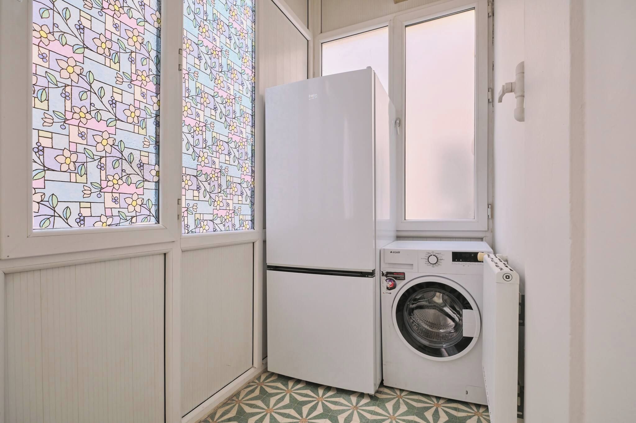 A compact laundry room with a white refrigerator and a front-loading washing machine.