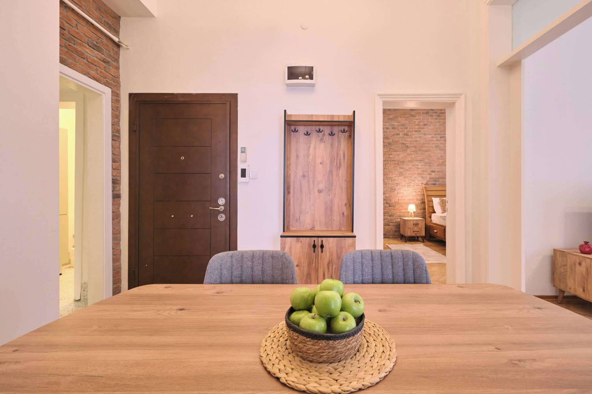 Un coin repas avec une table en bois, deux chaises et un panier de pommes vertes.