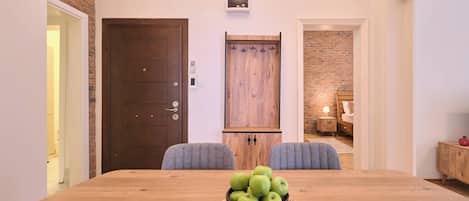 A dining area with a wooden table, two chairs, and a basket of green apples.