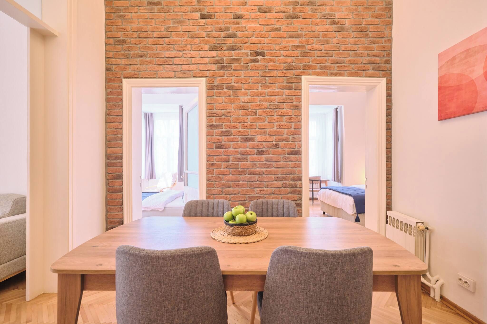 Un coin repas avec un mur en briques, une table en bois et deux chaises grises.