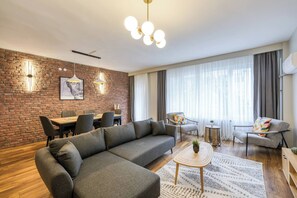 A modern living room with a sectional sofa, a dining area with a table and chairs, a coffee table, and a large window with curtains. - Prestige, Spacious, 3BR (Kadıköy)