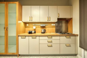 A compact kitchen with wooden cabinets, a stainless steel range hood, and a coffee maker. - Prestige, Spacious, 3BR (Kadıköy)