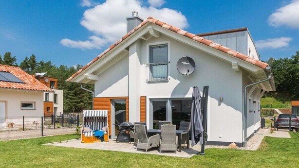 A modern two-story house with a patio area featuring outdoor furniture and a grill. - Holiday home with 1 bedroom (Krakow am See)