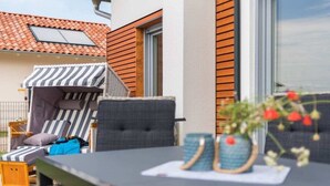 An outdoor seating area with a table, chairs, and a small garden. - Holiday home with 1 bedroom (Krakow am See)