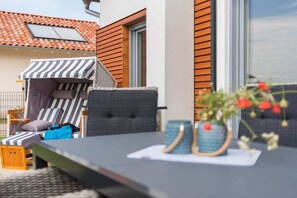 Ein Sitzbereich im Freien mit Tisch, Stühlen und einem kleinen Garten.