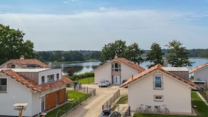 A residential area with houses, a lake, and a clear sky. - Holiday home with 1 bedroom (Krakow am See)