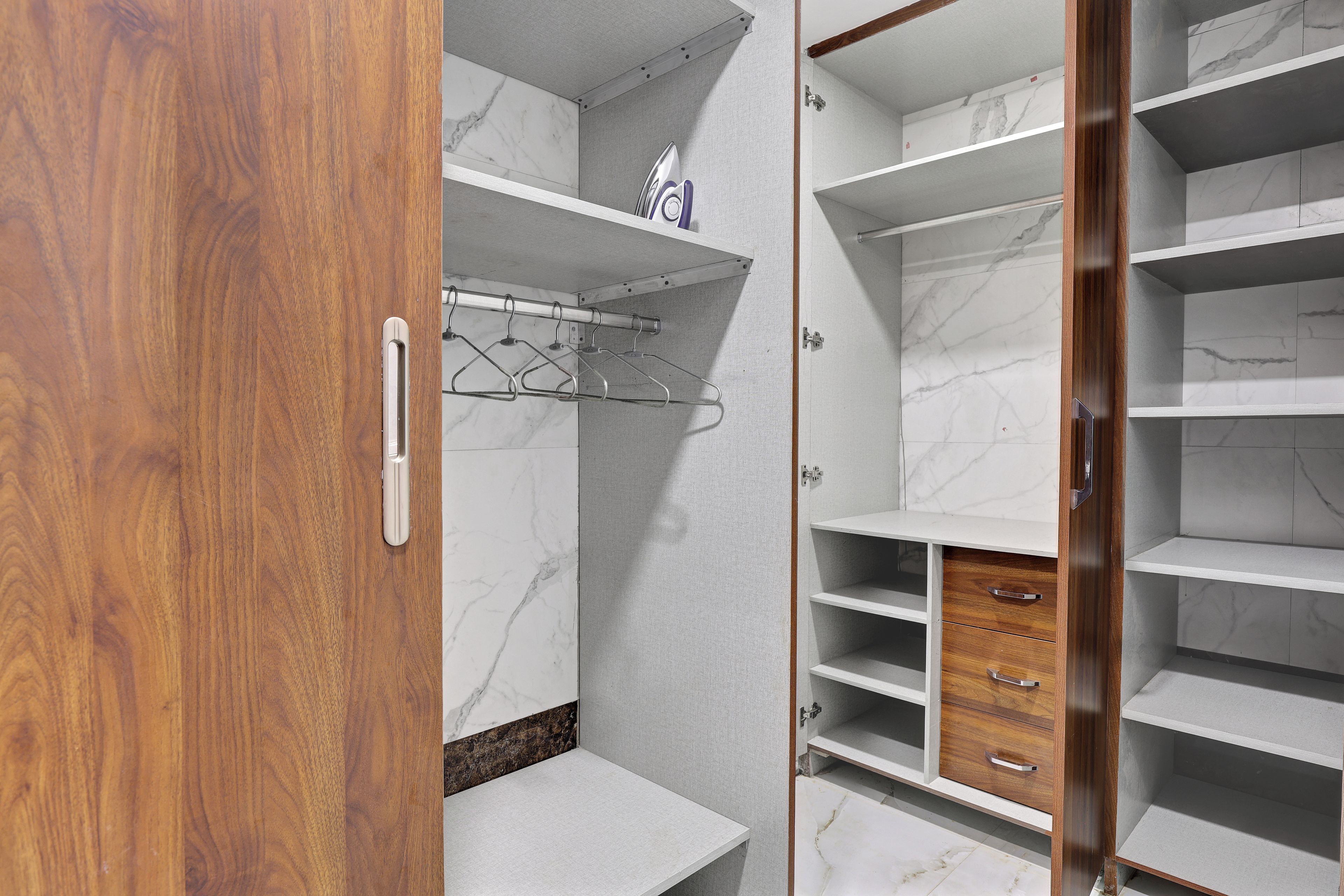 A walk-in closet with open doors, revealing shelves and drawers.