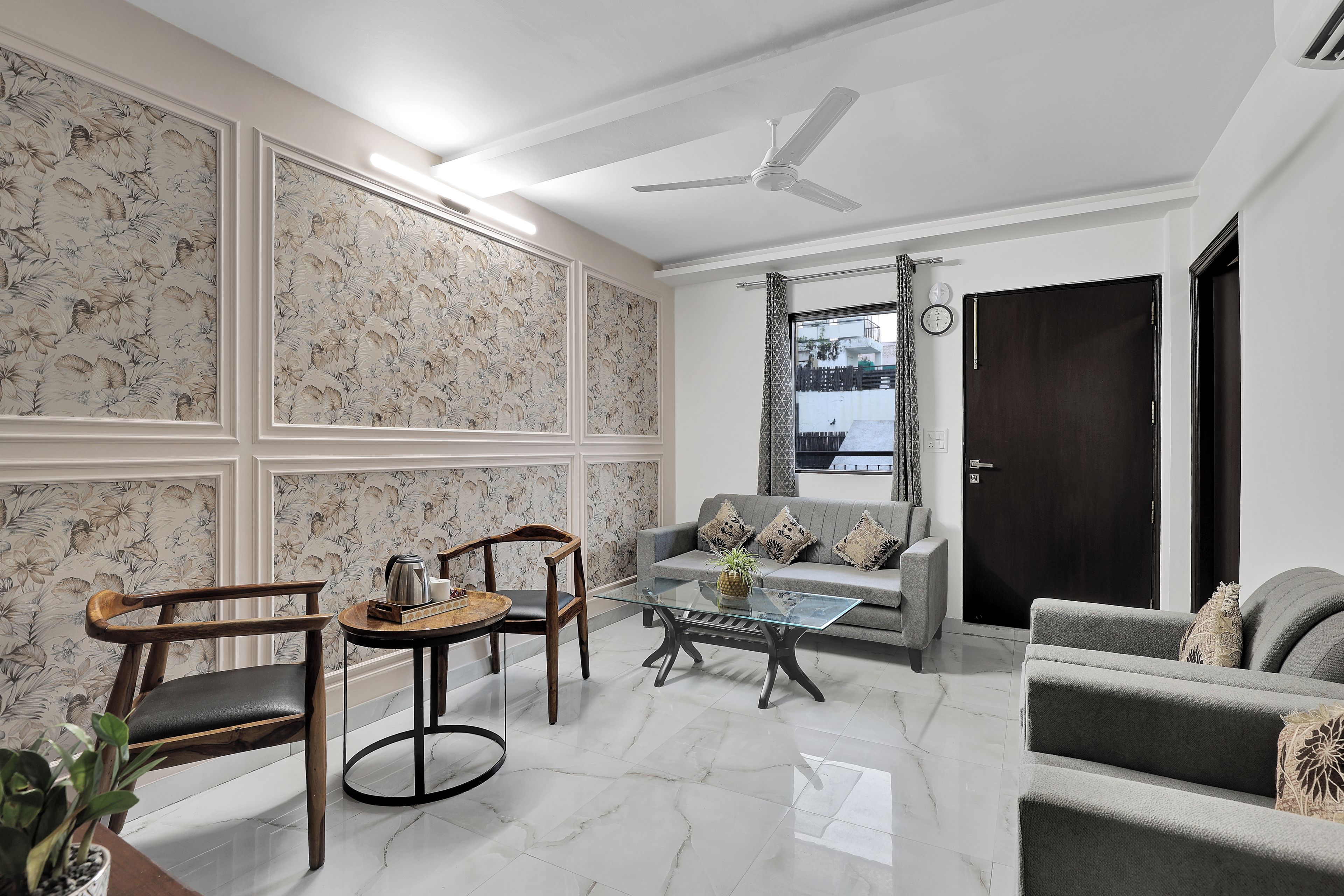 A modern living room with a sofa, chairs, a coffee table, and a ceiling fan.