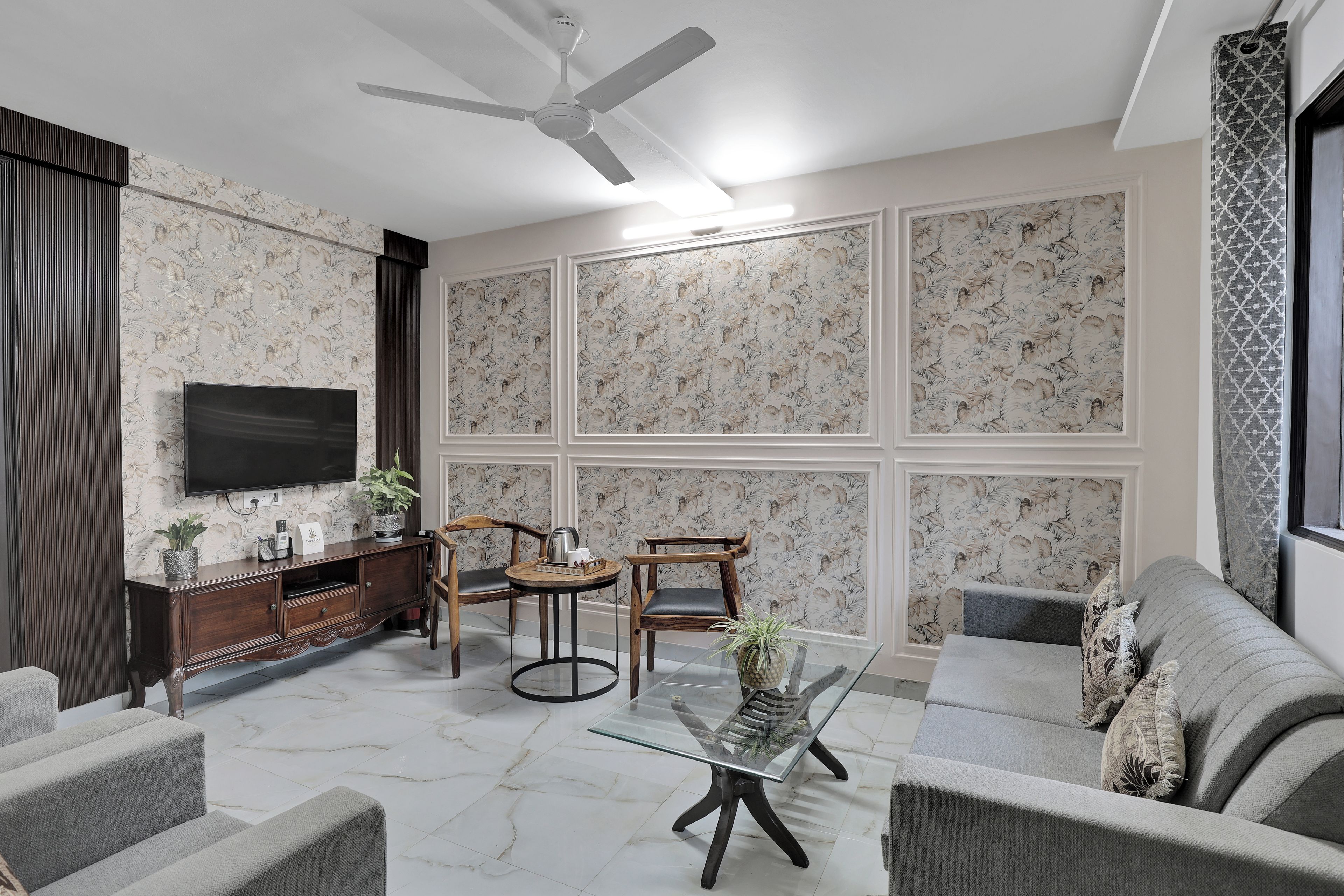 A modern living room with a flat-screen TV, a ceiling fan, a sofa, a coffee table, and a dining area with chairs.