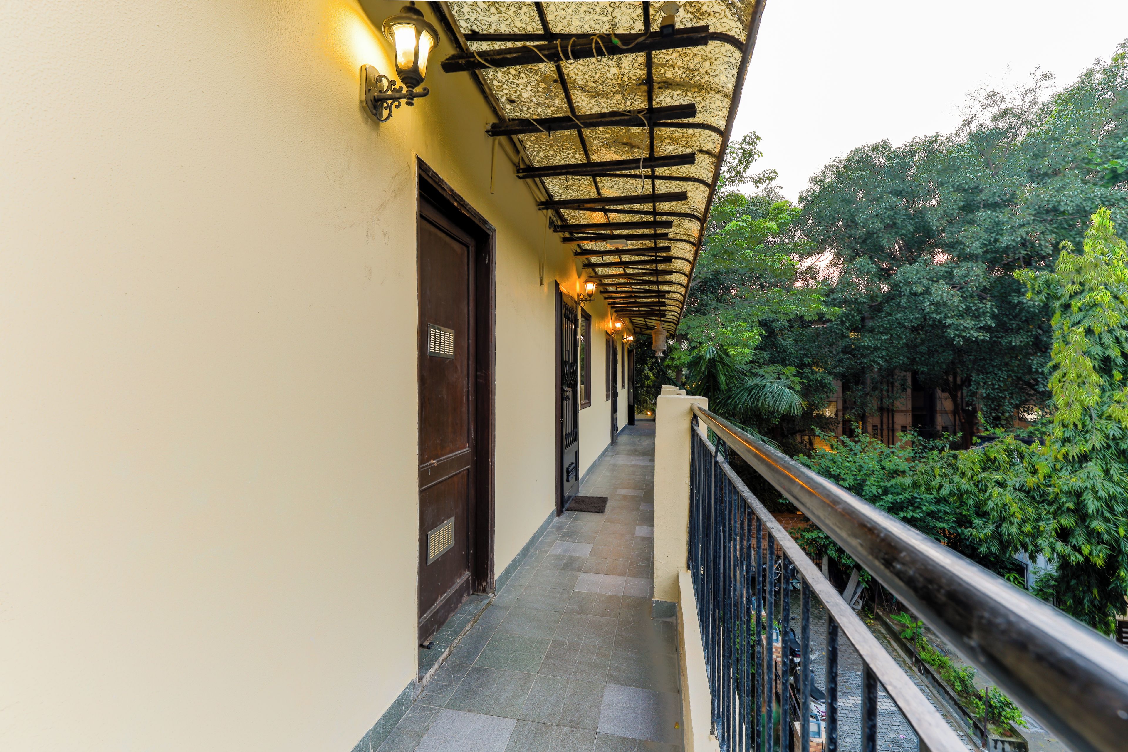 A corridor with a covered walkway, a railing, and a door.