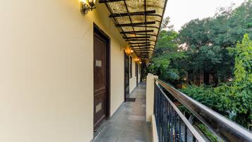 A corridor with a covered walkway, a railing, and a door.