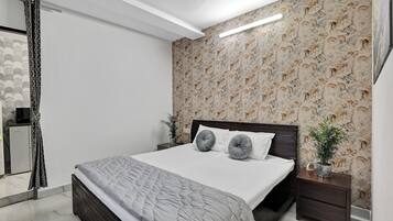 A modern bedroom with a large bed, a dark headboard, and a floral wallpaper.