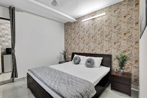 Un dormitorio moderno con una cama grande, cabecera oscura y papel tapiz floral.