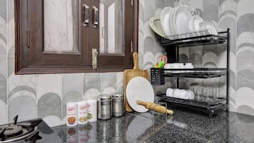 A kitchen with a wooden door, a spice rack, a dish rack, and a countertop with various kitchen items.