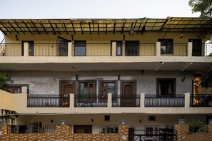 Un edificio de dos plantas con balcones, fachada de tejas y entrada protegida por una reja.
