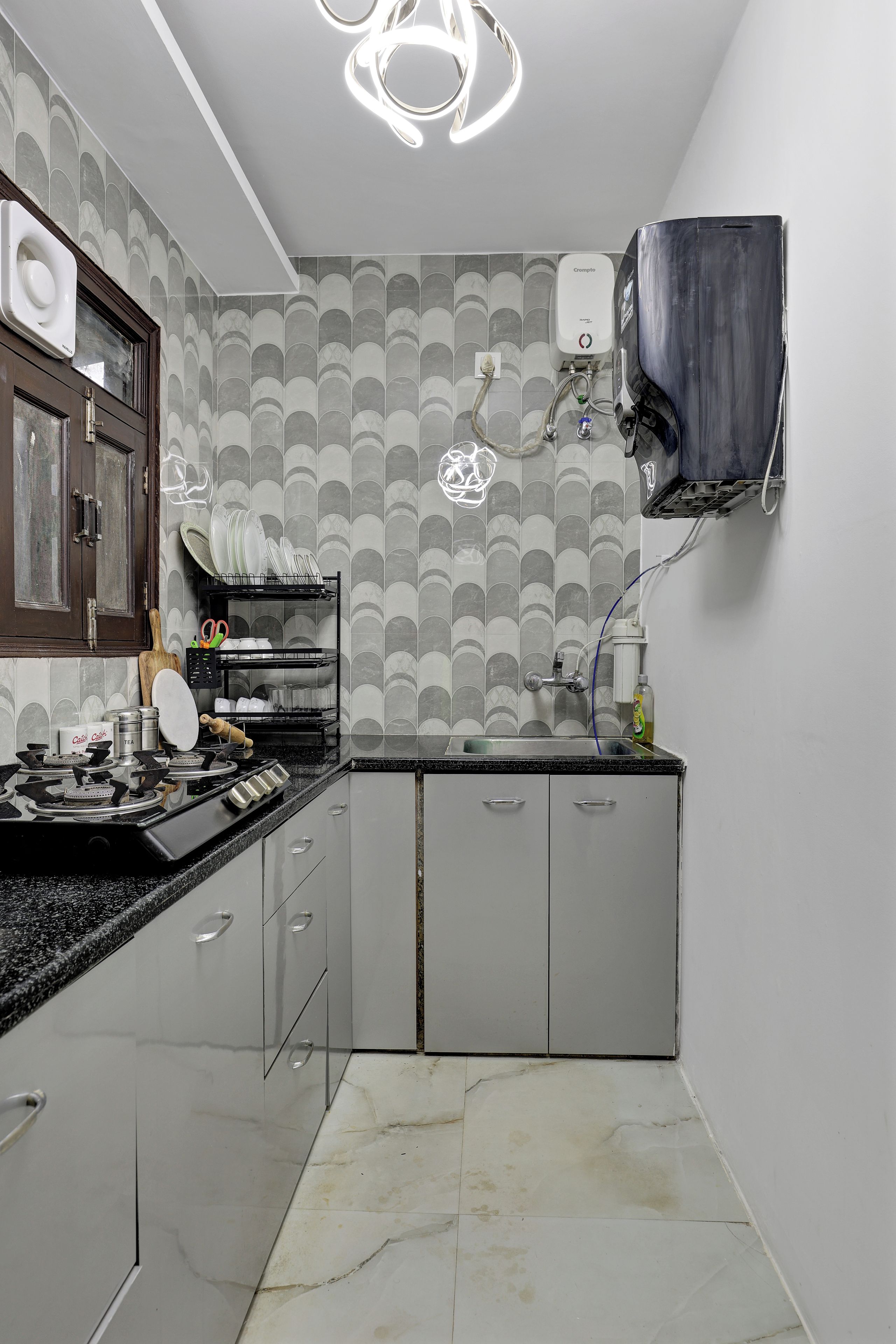 A compact kitchen with a gas stove, a sink, and a wall-mounted water heater.
