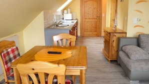 Un espacio habitable compacto con una mesa de comedor, sillas, un sofá, kitchenette y una puerta de madera.
