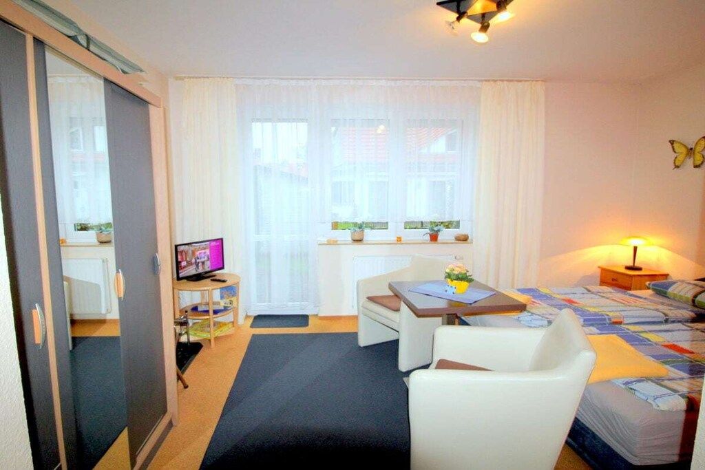 A hotel room with a bed, a desk, a chair, a television, and a window with curtains.