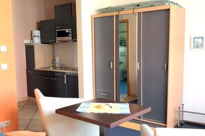 A compact room with a kitchenette, a wardrobe, and a small table with a towel. - Holiday room with terrace (Zingst)