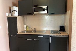 A compact kitchen with a microwave, coffee maker, and a sink. - Holiday room with terrace (Zingst)